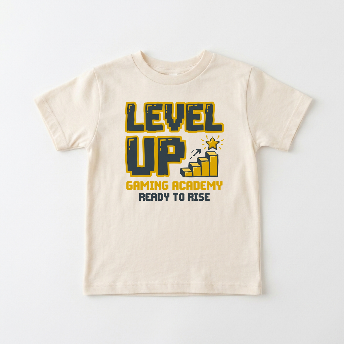 A cream-colored short-sleeve t-shirt with a graphic on the front that reads 'LEVEL UP GAMING ACADEMY READY TO RISE' in yellow and dark blue, accompanied by a small bar graph and star icon.