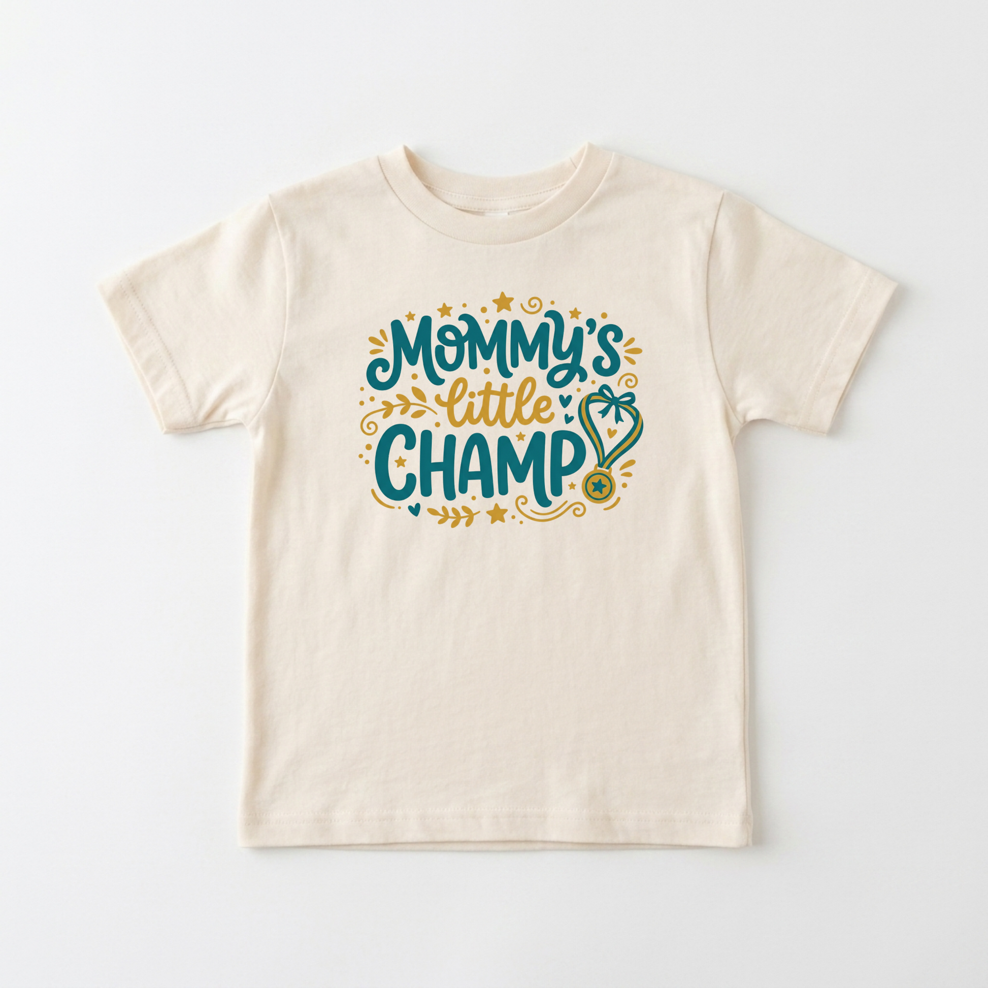 An off-white short-sleeve kids' t-shirt with a colorful graphic on the chest that reads 'Mommy's little CHAMP' in teal and gold lettering with decorative stars and a stethoscope.