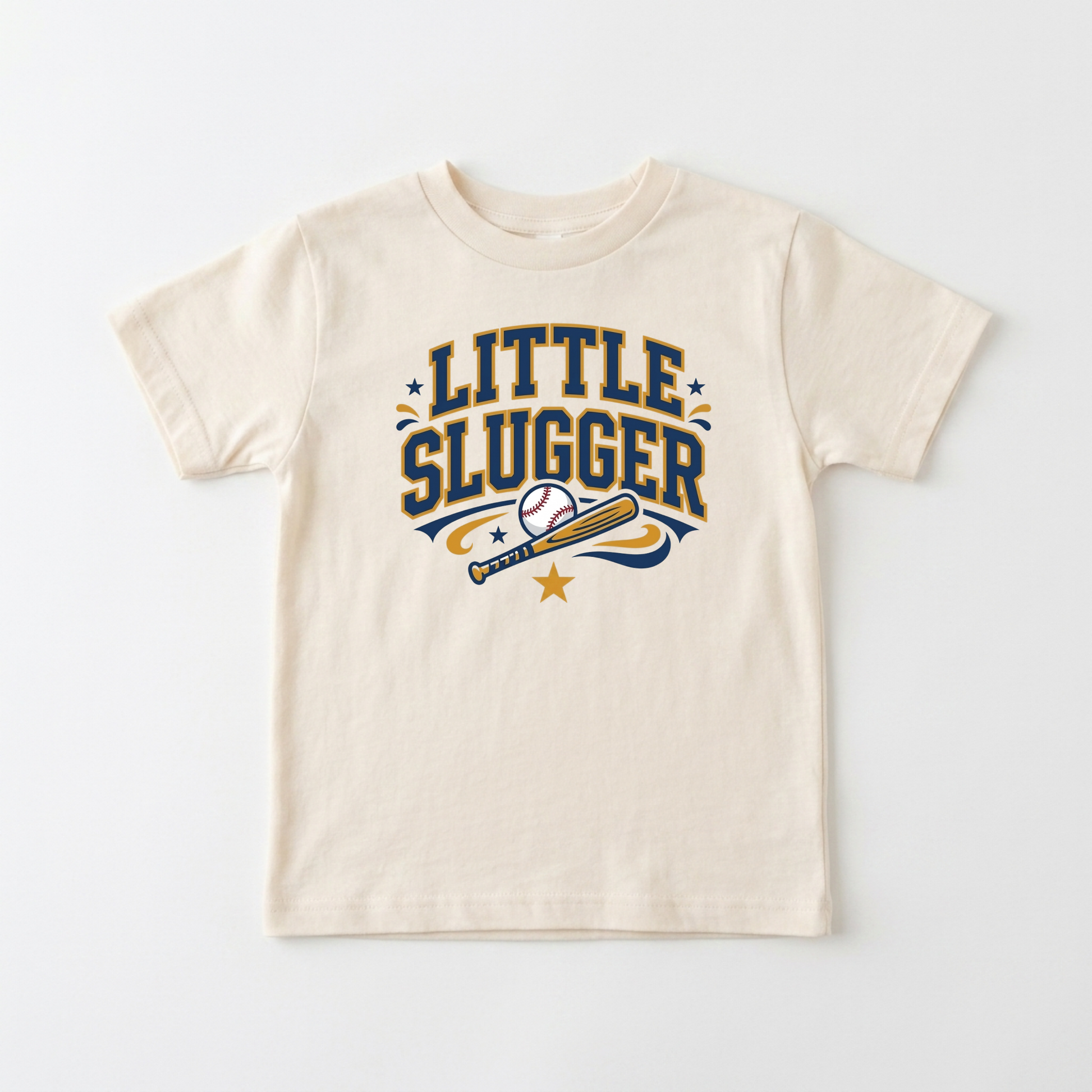 A cream-colored short-sleeve t-shirt with a 'LITTLE SLUGGER' baseball graphic in navy blue and gold, displayed flat against a light gray background.