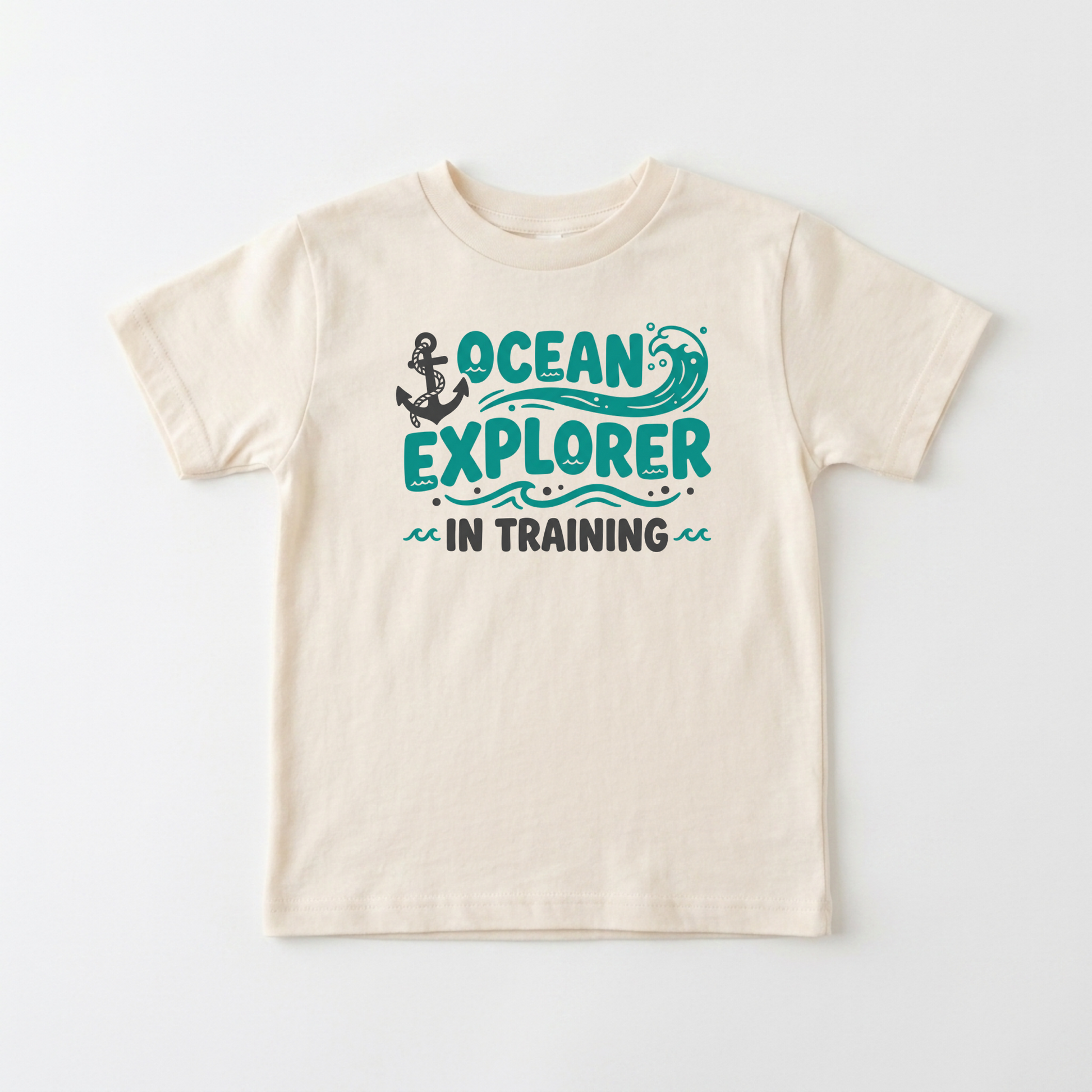 A cream-colored short-sleeve t-shirt with a graphic on the front that reads 'OCEAN EXPLORER IN TRAINING' in teal and dark gray, featuring an anchor and wave illustration, shown against a plain white background.