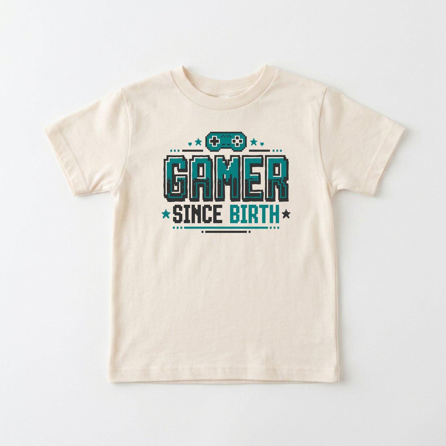 A cream-colored short-sleeve t-shirt with a 'GAMER SINCE BIRTH' graphic printed on the chest in teal and dark gray, displayed flat against a light gray background.