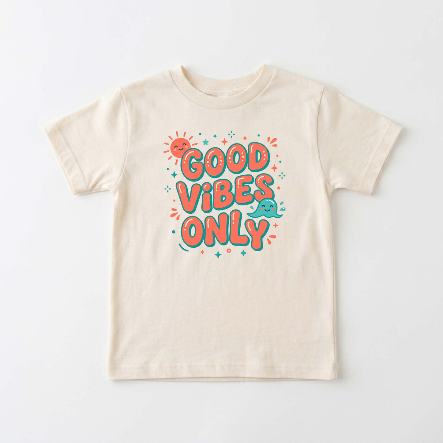 A cream-colored short-sleeve t-shirt with a colorful graphic on the front that reads 'GOOD VIBES ONLY' in bubbly orange letters with teal outlines, accompanied by a small smiling sun and teal cloud.