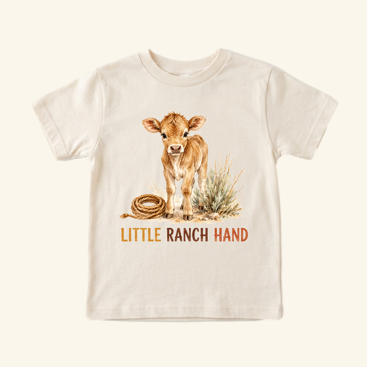 A cream-colored Little Ranch Hand Toddler Shirt – Western Baby Calf Country Tee featuring a watercolor illustration of a calf, a coiled rope, and the text LITTLE RANCH HAND.