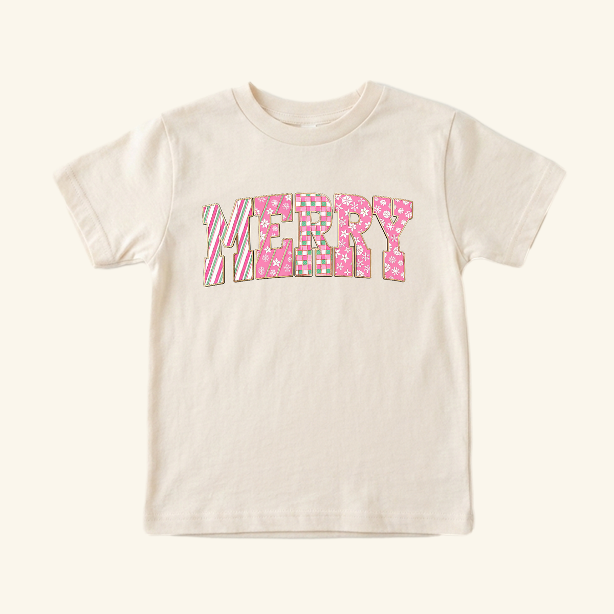 Toodleroos Merry Toddler Shirt – Pink Candy Cane Christmas Tee: a short-sleeved cream shirt with the word MERRY printed on the chest in a festive pink, white, and green patterned font.