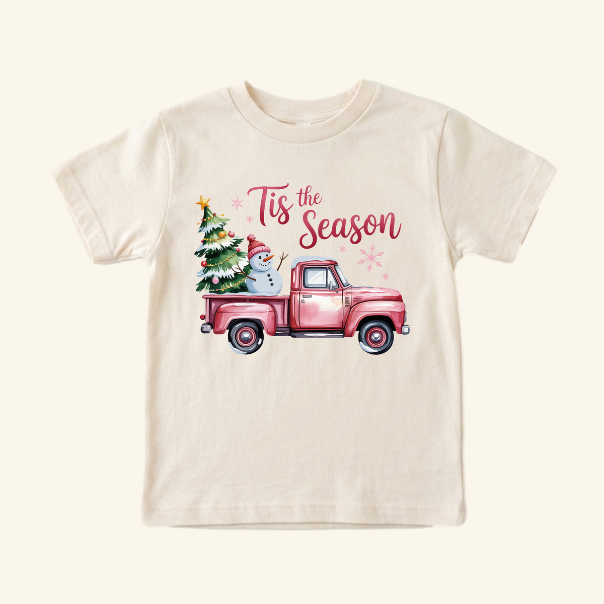 Toodleroos Pink Christmas Truck Toddler Shirt – ’Tis the Season Snowman Tee in cream, featuring a pink Christmas truck carrying a snowman and a tree, with Tis the Season written above it.