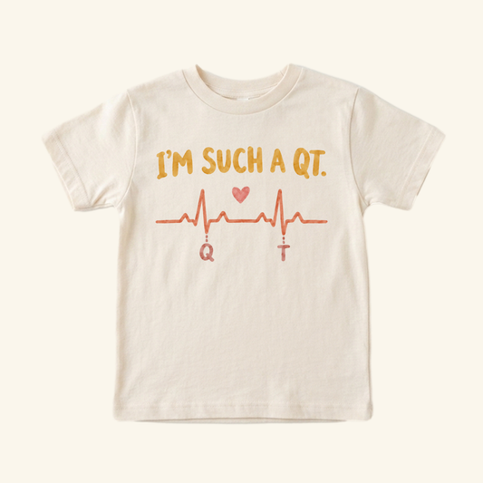 Cream I’m Such a QT Toddler Shirt featuring an EKG line with a heart and the letters Q and T below the peaks.