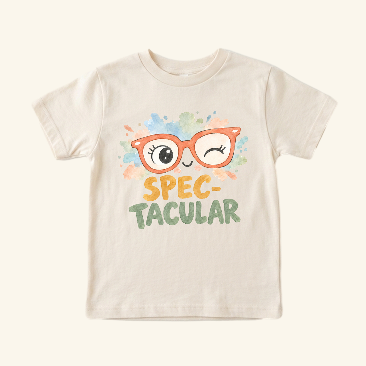 Cream-colored Spec-tacular Toddler Shirt – Cute Winking Glasses Tee featuring a confidence-boosting graphic of orange eyeglasses with a winking eye, colorful watercolor splotches, and the text SPEC-TACULAR.