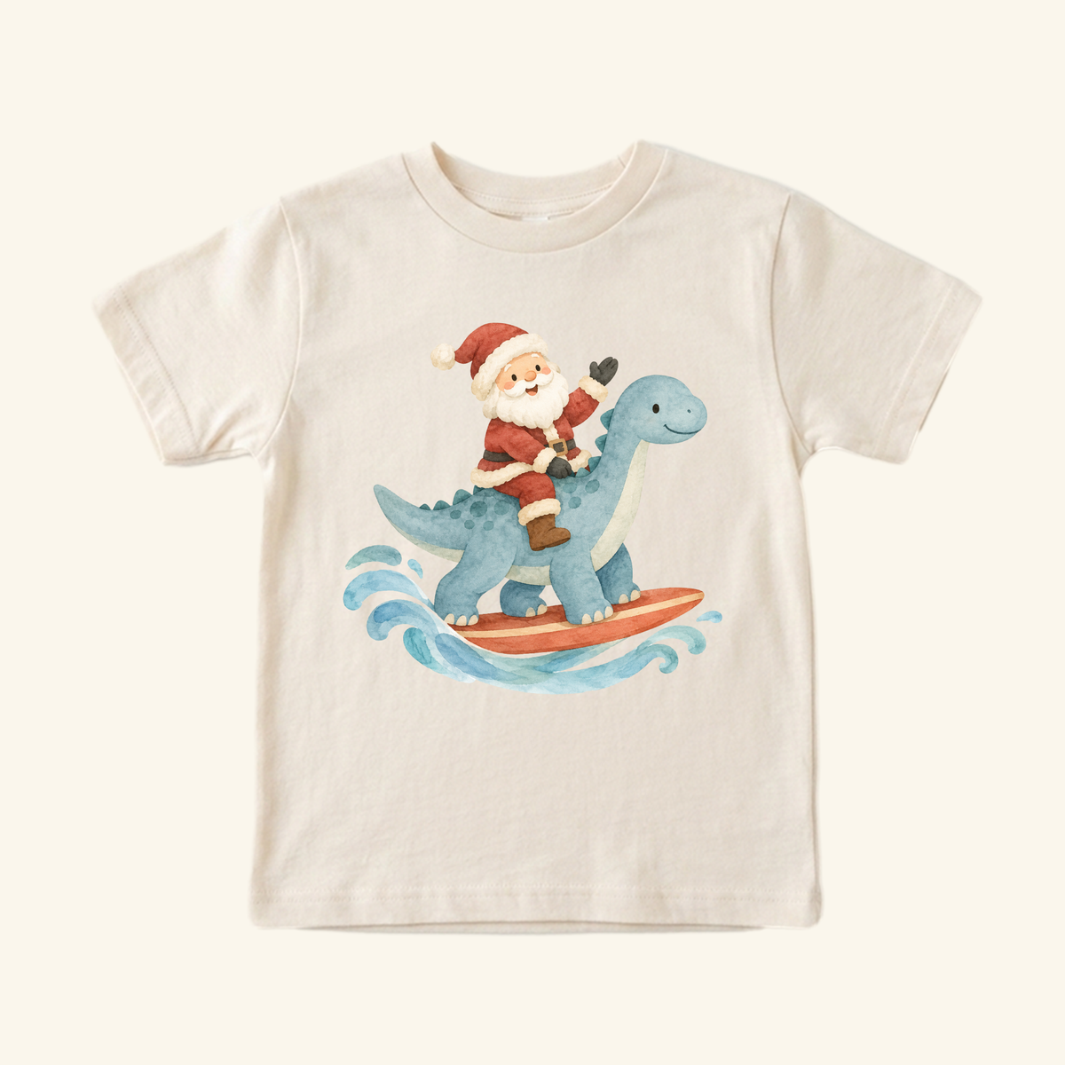 Light-colored Santa Surfing Dinosaur Toddler Shirt – Christmas Beach Tee featuring a watercolor illustration of Santa surfing on the back of a blue dinosaur.
