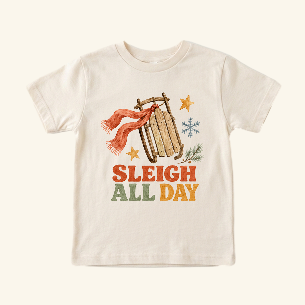 Off-white Toodleroos Sleigh All Day Toddler Shirt – Retro Christmas Sled Tee featuring a retro Christmas sled illustration with a red scarf, stars, and snowflakes above the text SLEIGH ALL DAY.