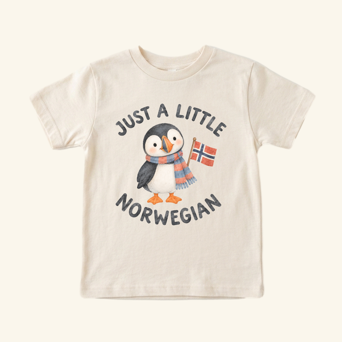 Just a Little Norwegian Toddler Shirt – Cute Puffin Norway Flag Tee featuring a watercolor illustration of a puffin in a striped scarf holding a Norwegian flag, with Just a little Norwegian text above and below.