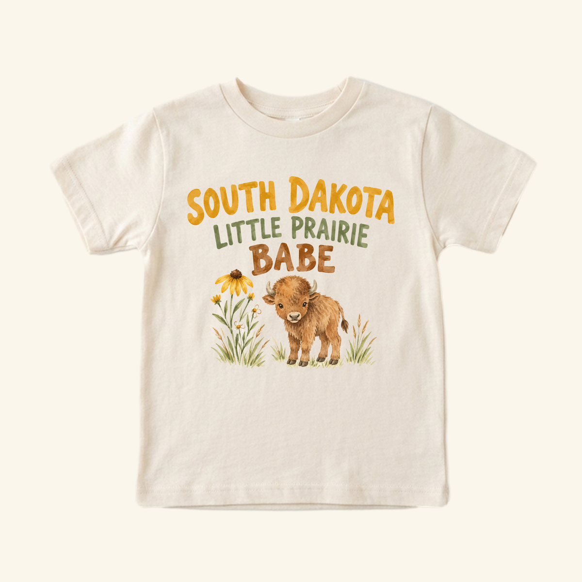 Cream-colored South Dakota Toddler Shirt – Little Prairie Babe Buffalo Tee featuring a graphic of a bison calf, a wildflower, and the text South Dakota Little Prairie Babe.