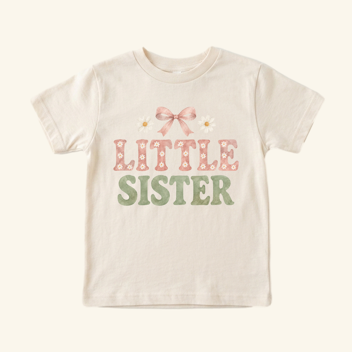 Cream-colored Toodleroos Little Sister Toddler Shirt – Daisy Bow Sibling Tee featuring a pink bow, two daisies, and text in pink and green.
