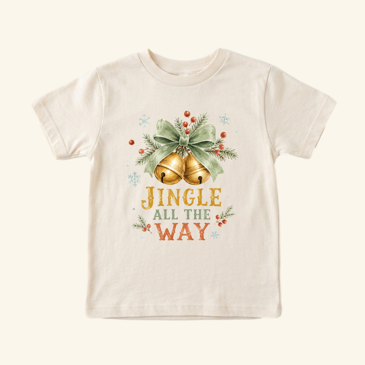 Jingle All the Way Toddler Shirt – Vintage Christmas Jingle Bells Tee featuring a cream t-shirt with a vintage illustration of golden bells, a green ribbon, pine needles, berries, and the text JINGLE ALL THE WAY in gold and red.
