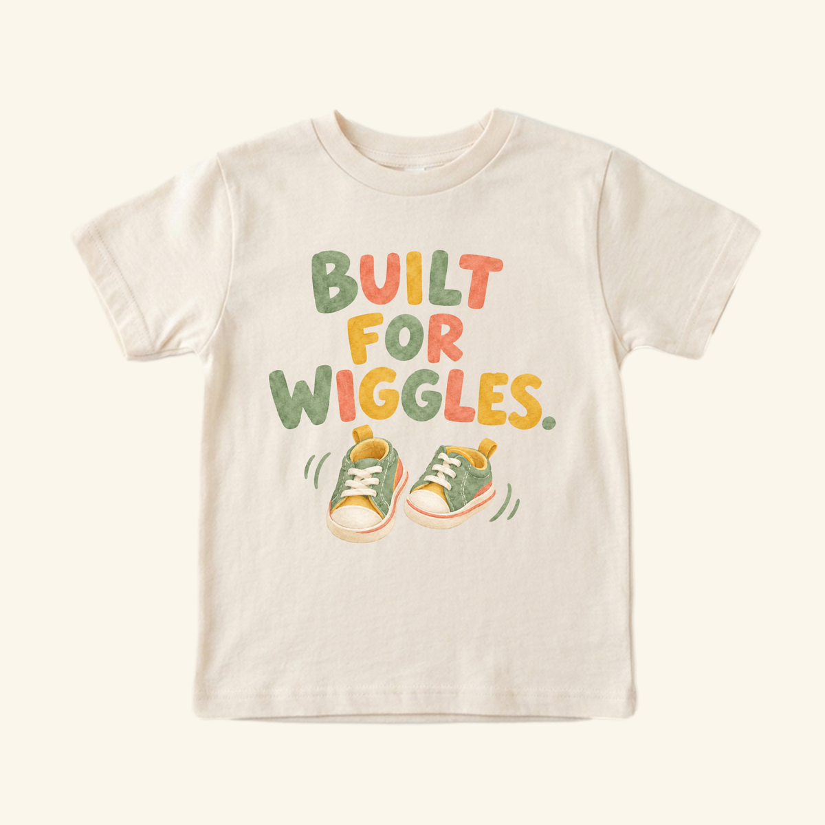Cream Built for Wiggles Toddler Shirt with the text BUILT FOR WIGGLES above a pair of green sneakers with motion lines.