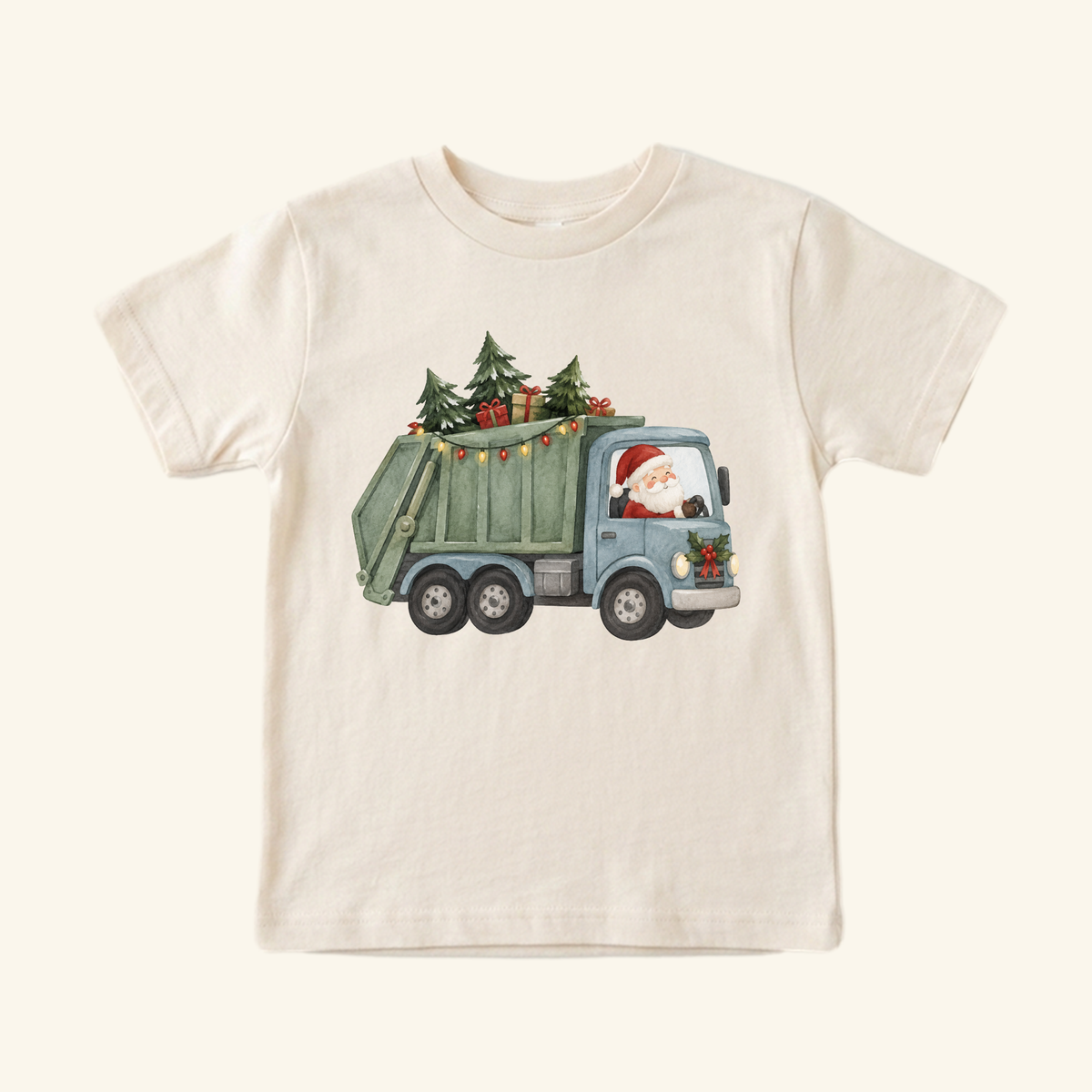 A cream-colored Santa Garbage Truck Toddler Shirt – Christmas Trash Truck Tee featuring an illustration of Santa Claus driving a garbage truck loaded with Christmas trees, presents, and string lights.