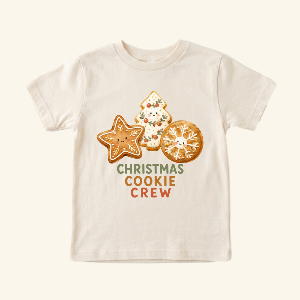 Cream-colored Christmas Cookie Crew Toddler Shirt featuring a print of three smiling holiday cookies.