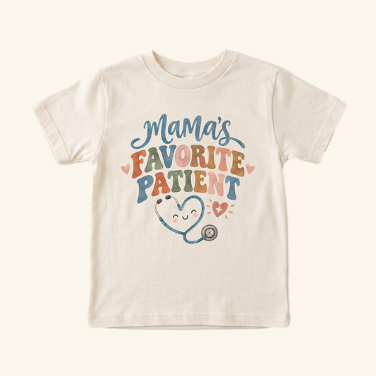 Cream-colored Mama’s Favorite Patient Toddler Shirt featuring a cartoon stethoscope shaped like a heart and the text Mama’s Favorite Patient.