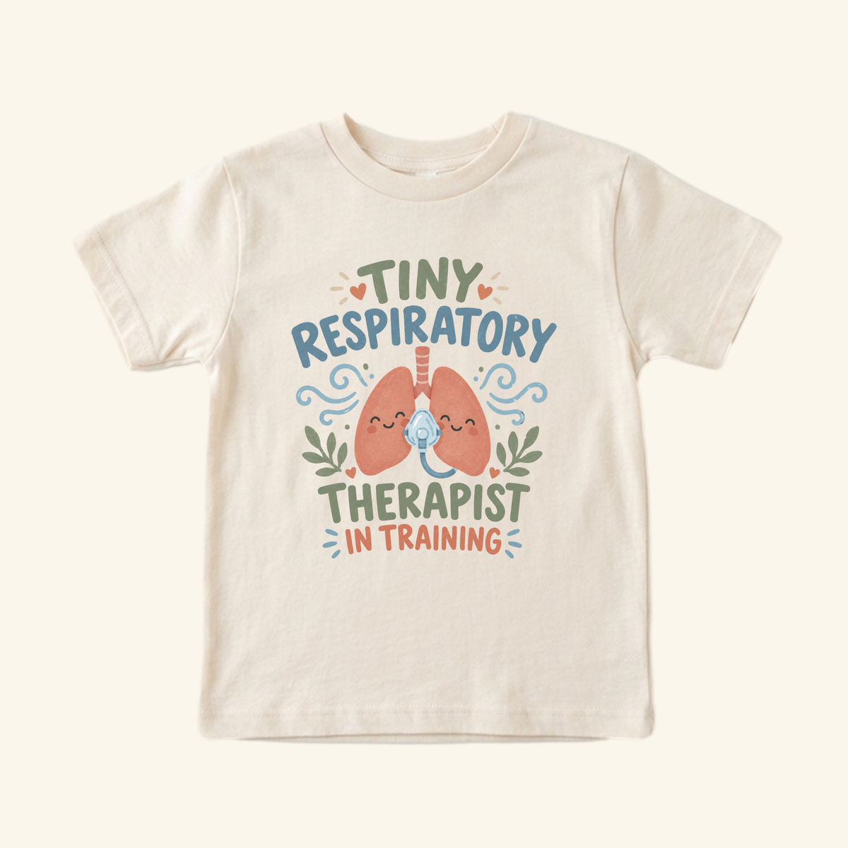Cream-colored Tiny Respiratory Therapist in Training Toddler Shirt – Cute RT Tee featuring a graphic of smiling lungs wearing an oxygen mask and the text Tiny Respiratory Therapist in Training.