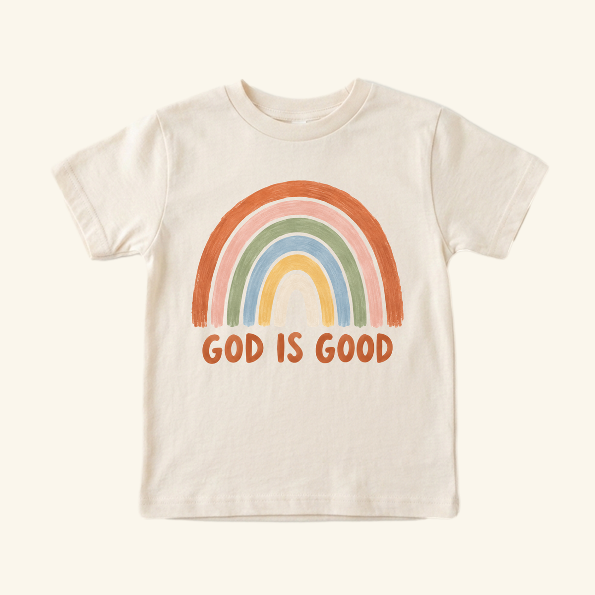 The Christian Toddler Shirt – God Is Good Rainbow Tee by Toodleroos is a cream shirt with an earthy rainbow and bold orange GOD IS GOOD text—perfect for little ones!.