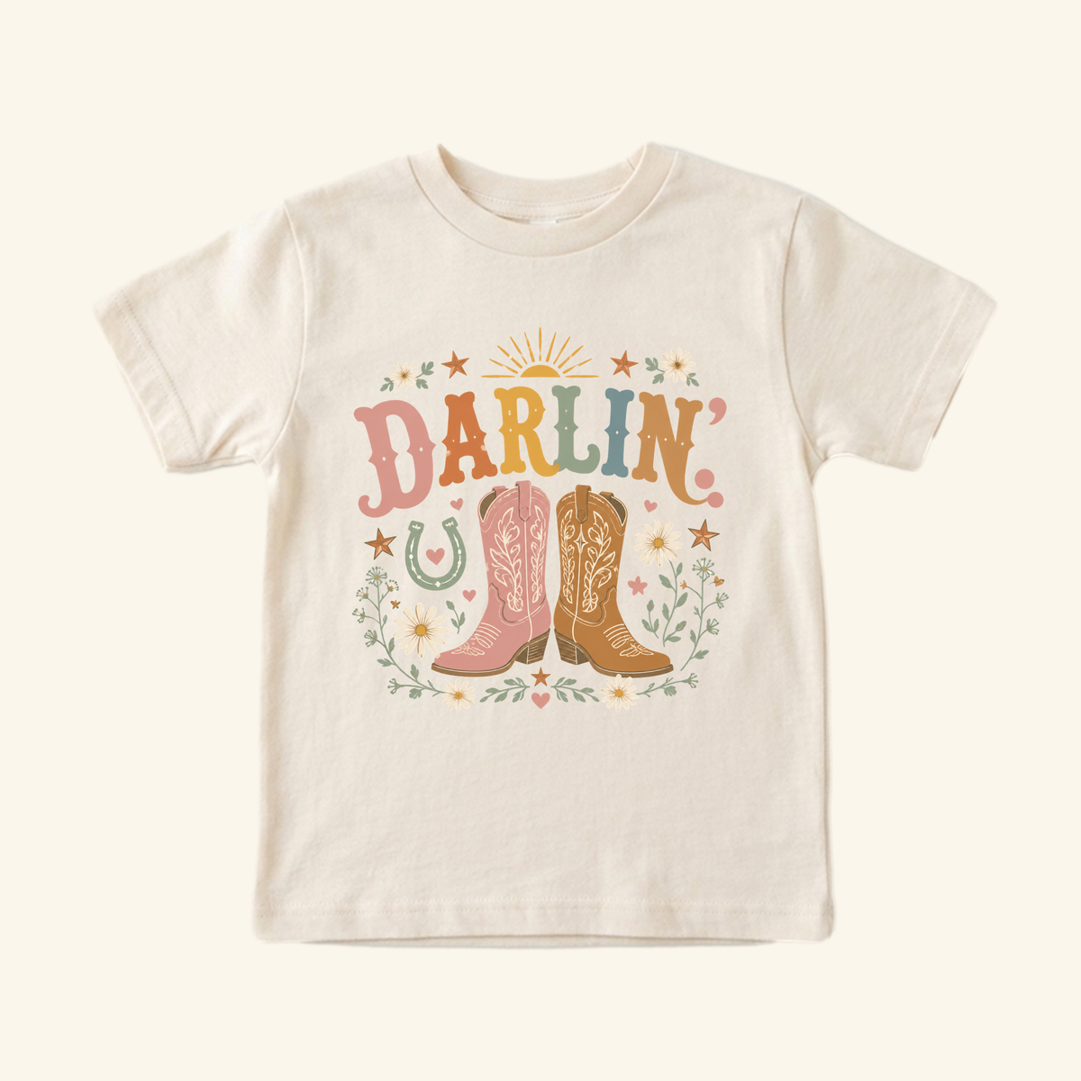 Toddler Cowgirl Shirt – Darlin’ Western Cowboy Boots Short-Sleeve Tee in cream, featuring a graphic print of two cowboy boots, wildflowers, and the word DARLIN in colorful retro lettering.