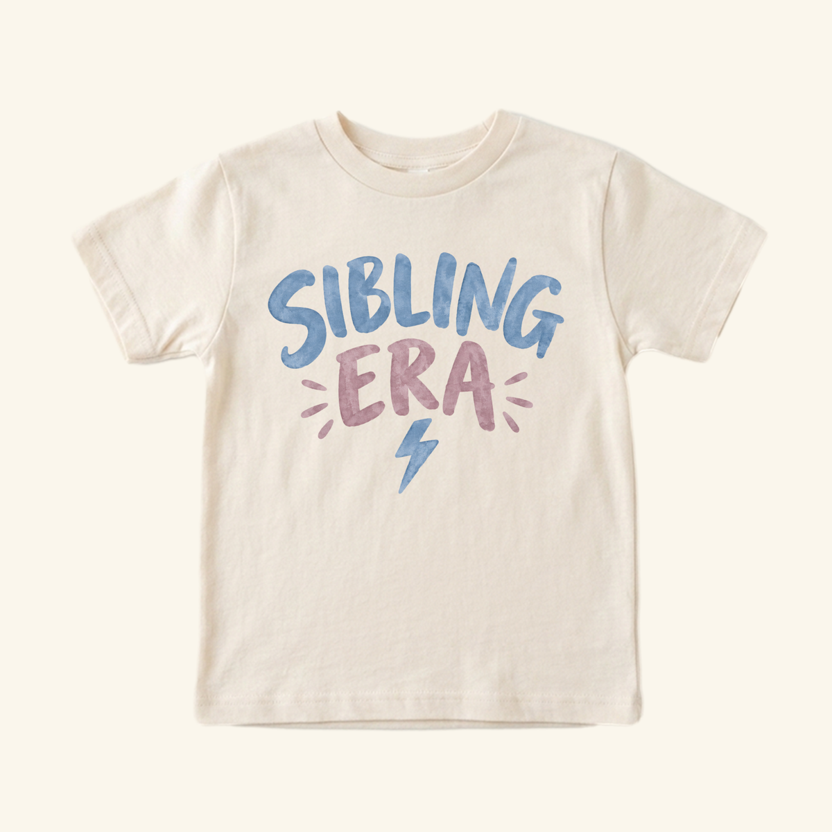 Toodleroos Sibling Era Toddler Shirt featuring cream-colored fabric with SIBLING ERA in blue and purple watercolor-style lettering above a small blue lightning bolt.