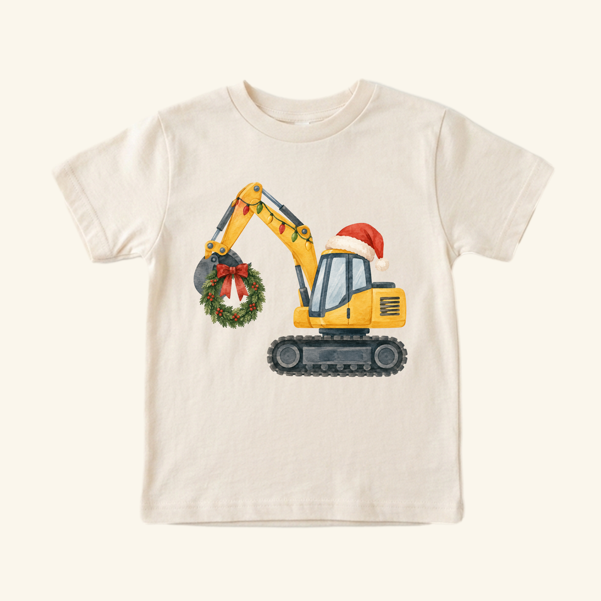 Christmas Excavator Toddler Shirt – Holiday Construction Tee: a cream toddler t-shirt featuring a yellow excavator wearing a Santa hat, with Christmas lights on its arm and a wreath hanging from its bucket.