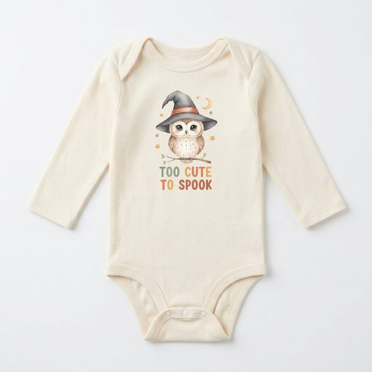 Dress your little one for their first Halloween in the Long-Sleeve Halloween Baby Onesie – Too Cute to Spook Owl Bodysuit from Toodleroos. This cream-colored baby bodysuit features a delightful illustration of an owl wearing a witch hat, surrounded by stars and a crescent moon, with the phrase “TOO CUTE TO SPOOK” printed below. An adorable and festive choice for your baby’s Halloween wardrobe!.