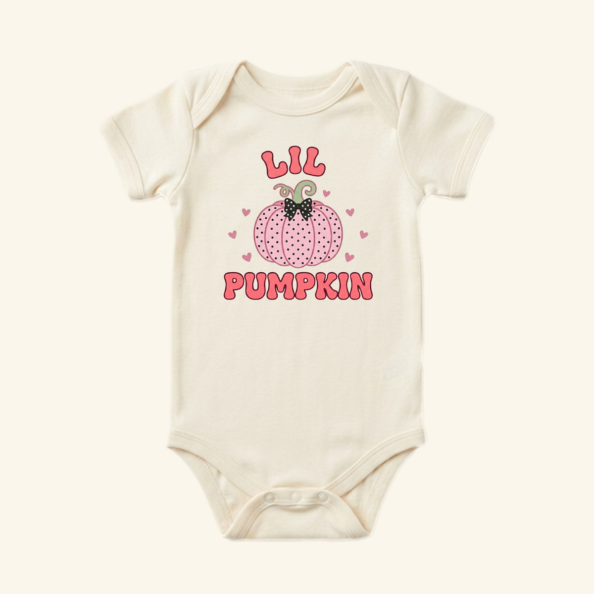 Lil Pumpkin Baby Girl Onesie – Fall Pumpkin Bodysuit in cream, featuring a pink polka-dot pumpkin with a black bow, surrounded by hearts and the text LIL PUMPKIN.