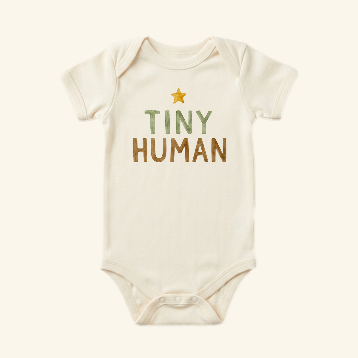 Cream-colored Toodleroos Tiny Human Baby Onesie – Minimalist Star Bodysuit featuring a small yellow star above the text TINY HUMAN in green and brown letters.
