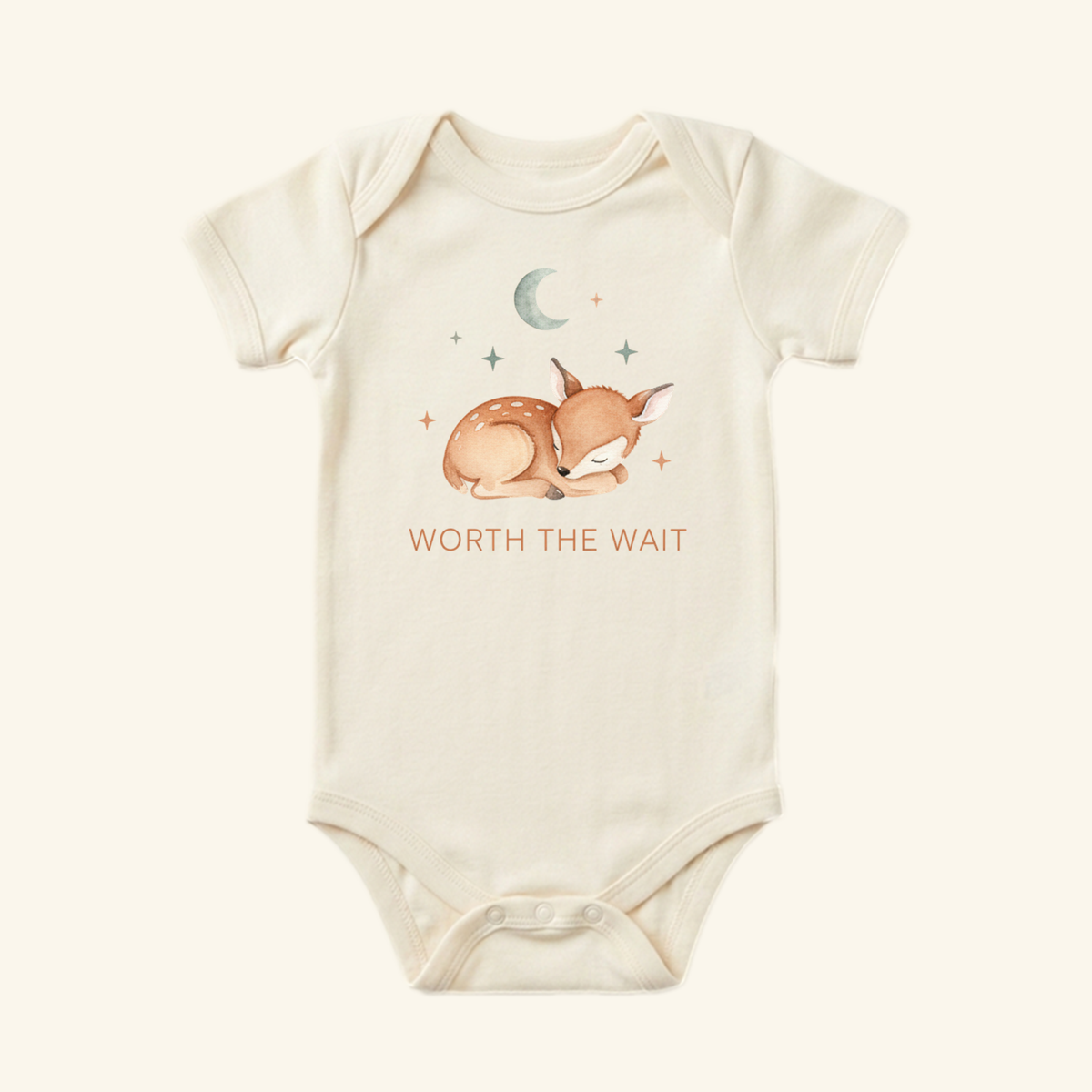 Cream-colored Worth the Wait Baby Onesie – Sleeping Deer Bodysuit featuring a watercolor illustration of a sleeping fawn beneath a crescent moon and stars.