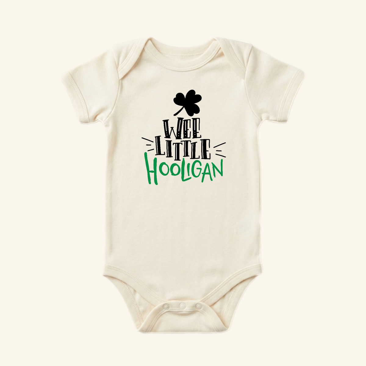Cream-colored St. Patrick’s Day Baby Onesie – Wee Little Hooligan Bodysuit featuring a black shamrock and St. Patrick’s Day-themed text in black and green.