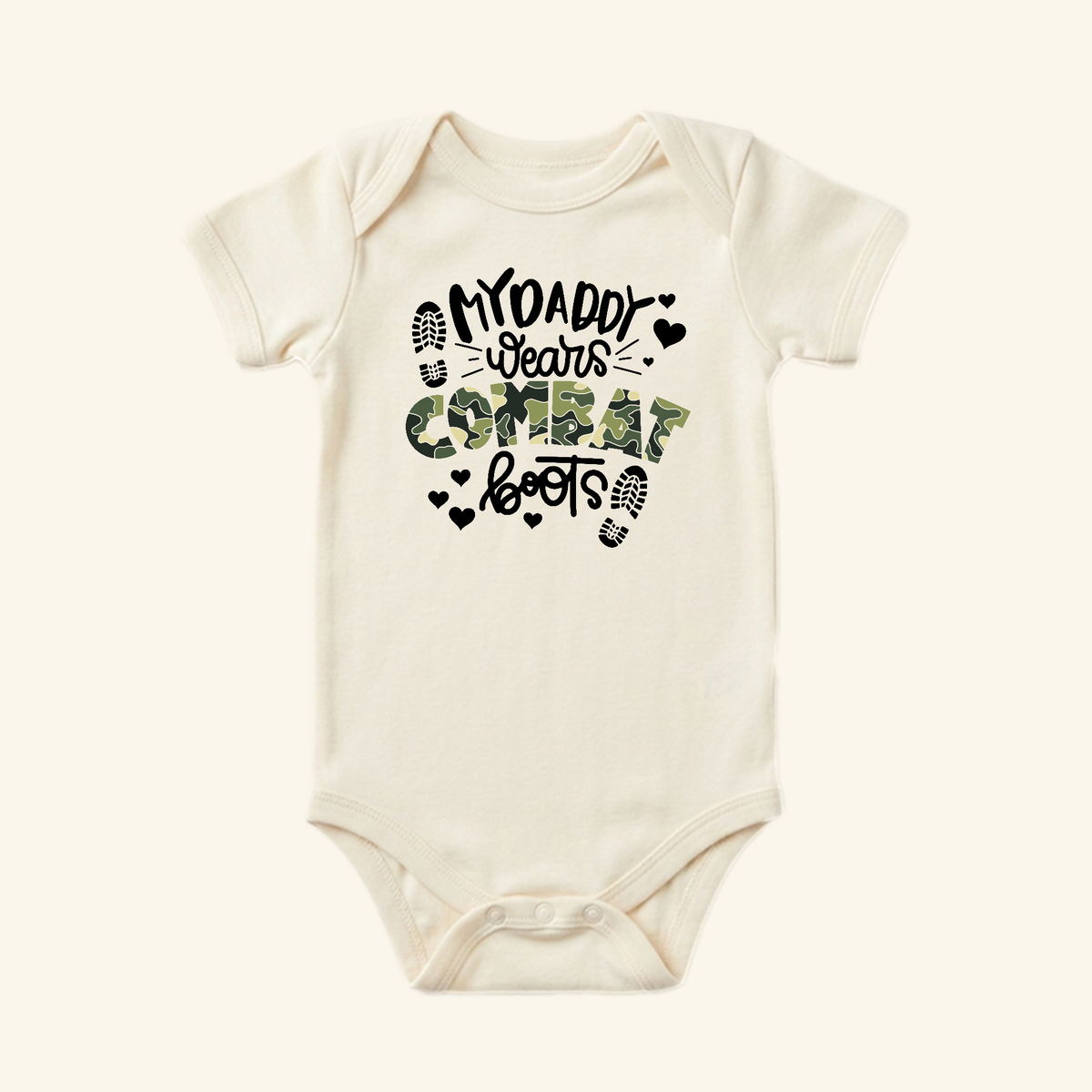Cream-colored Toodleroos Military Baby Onesie – My Daddy Wears Combat Boots Bodysuit featuring black and camouflage lettering that reads My daddy wears combat boots, accented by heart and boot-print icons.