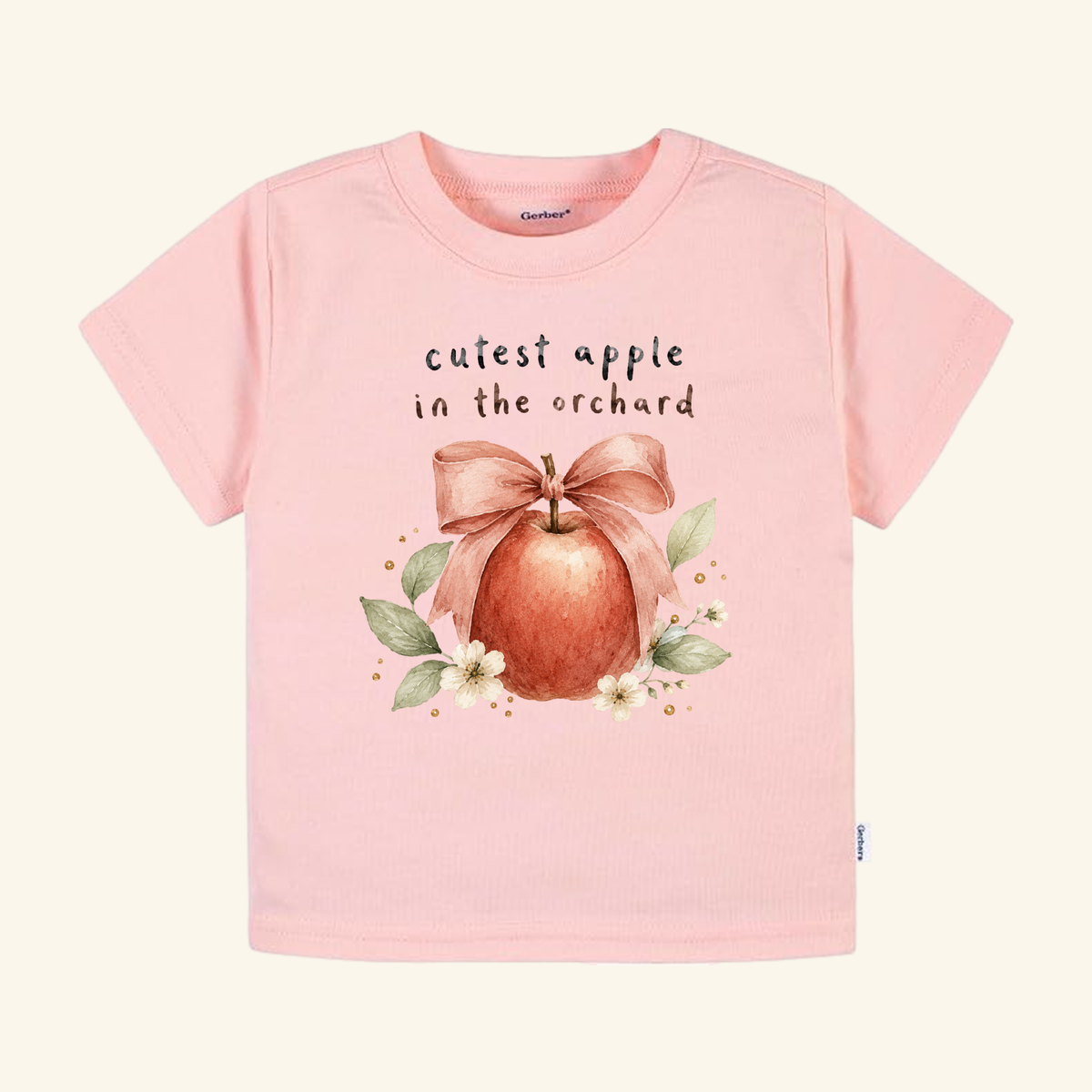 Pink Cutest Apple in the Orchard Toddler Shirt – Fall Apple Bow Tee featuring a watercolor apple with a bow, surrounded by leaves and flowers, and the text cutest apple in the orchard.