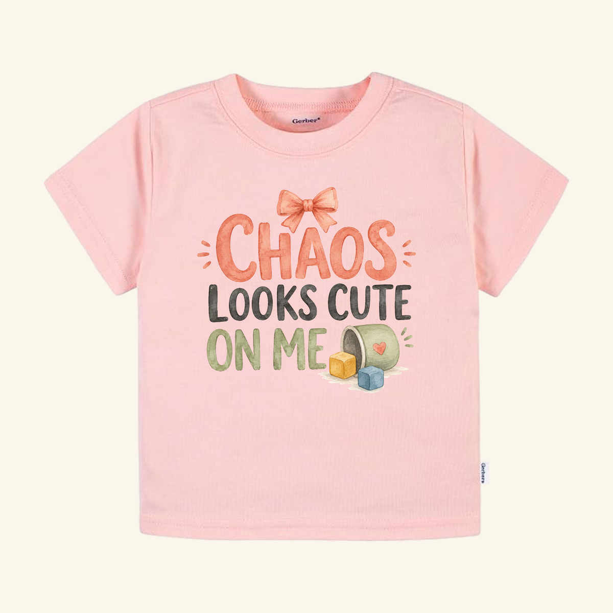 Light pink Chaos Looks Cute on Me Toddler Shirt featuring a bow graphic and the text Chaos Looks Cute on Me next to scattered blocks.