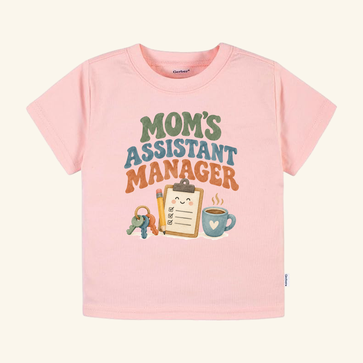 Light pink Mom’s Assistant Manager Toddler Shirt featuring a retro graphic of a clipboard, pencil, keys, and coffee mug.