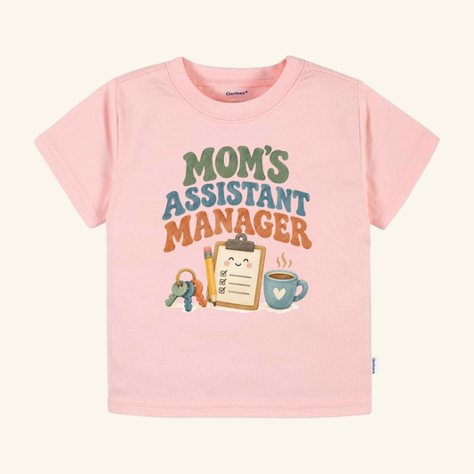 Light pink Mom’s Assistant Manager Toddler Shirt featuring a retro graphic of a clipboard, pencil, keys, and coffee mug.