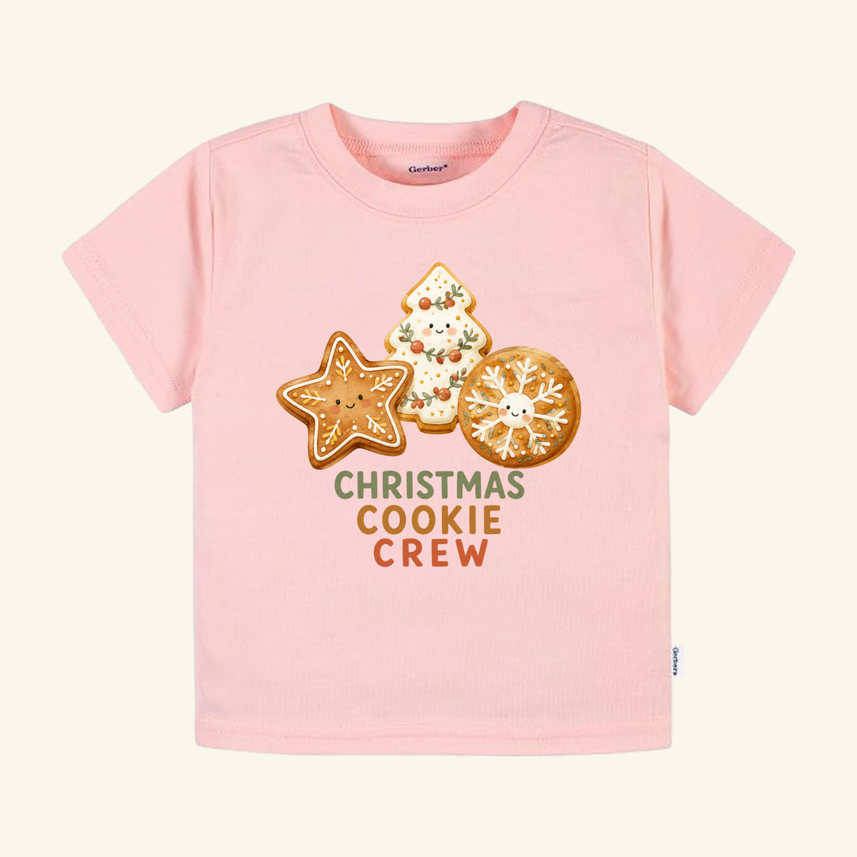 Light pink Toodleroos Christmas Cookie Crew Toddler Shirt featuring three illustrated holiday cookies with faces and the text CHRISTMAS COOKIE CREW underneath.
