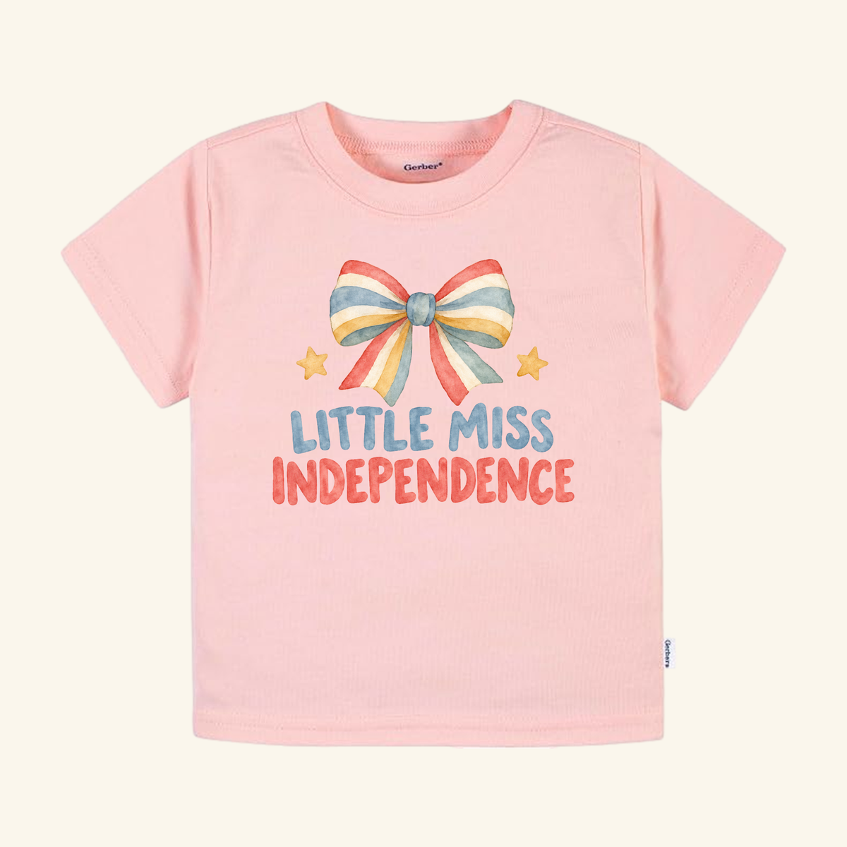 Light pink Little Miss Independence Toddler Shirt – Patriotic Bow Tee featuring a watercolor graphic of a red, white, and blue striped bow, two small stars, and the text Little Miss Independence.