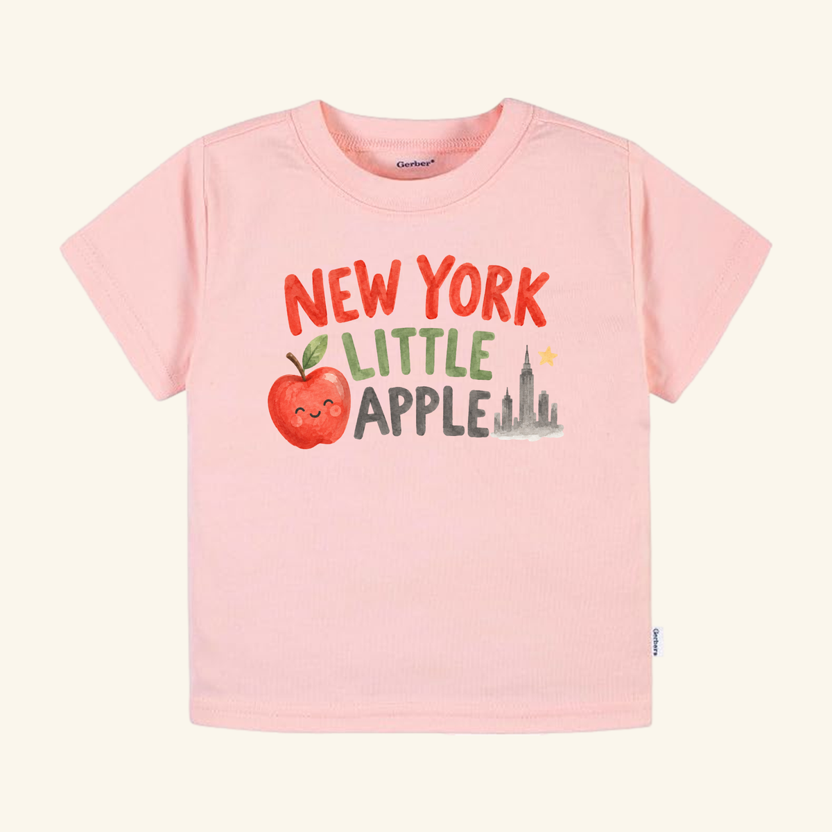 Light pink Toodleroos New York Toddler Shirt – Little Apple Skyline Watercolor Tee featuring a watercolor graphic of a smiling apple, a New York City skyline, a star, and the text NEW YORK LITTLE APPLE.