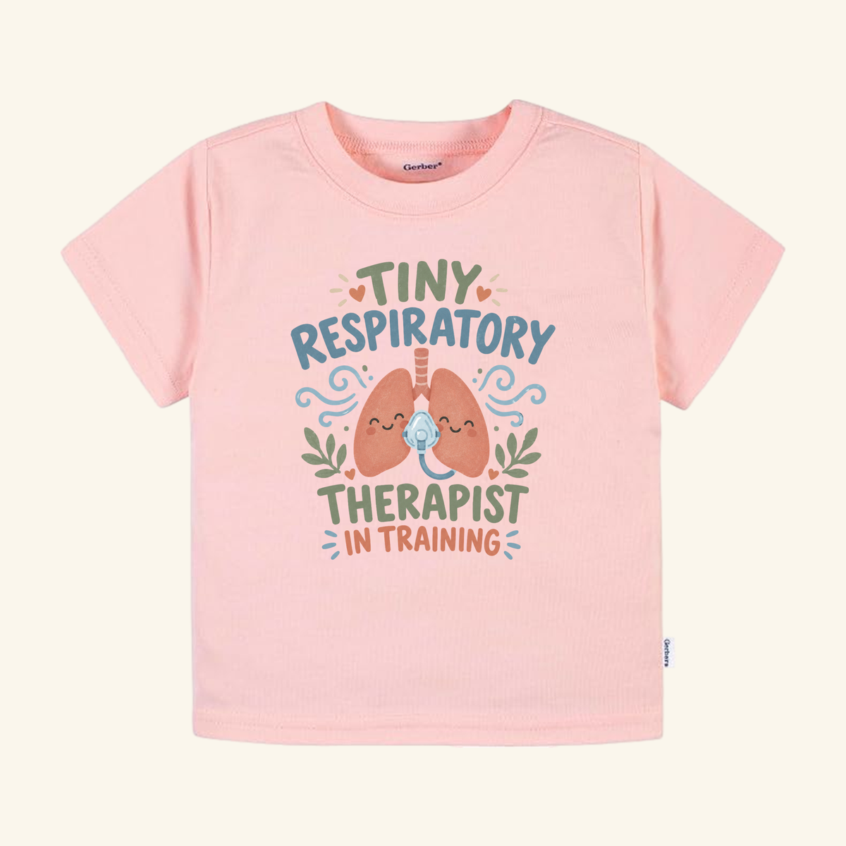 Light pink Tiny Respiratory Therapist in Training Toddler Shirt featuring a graphic of cartoon lungs wearing an oxygen mask, surrounded by text that reads Tiny Respiratory Therapist In Training.