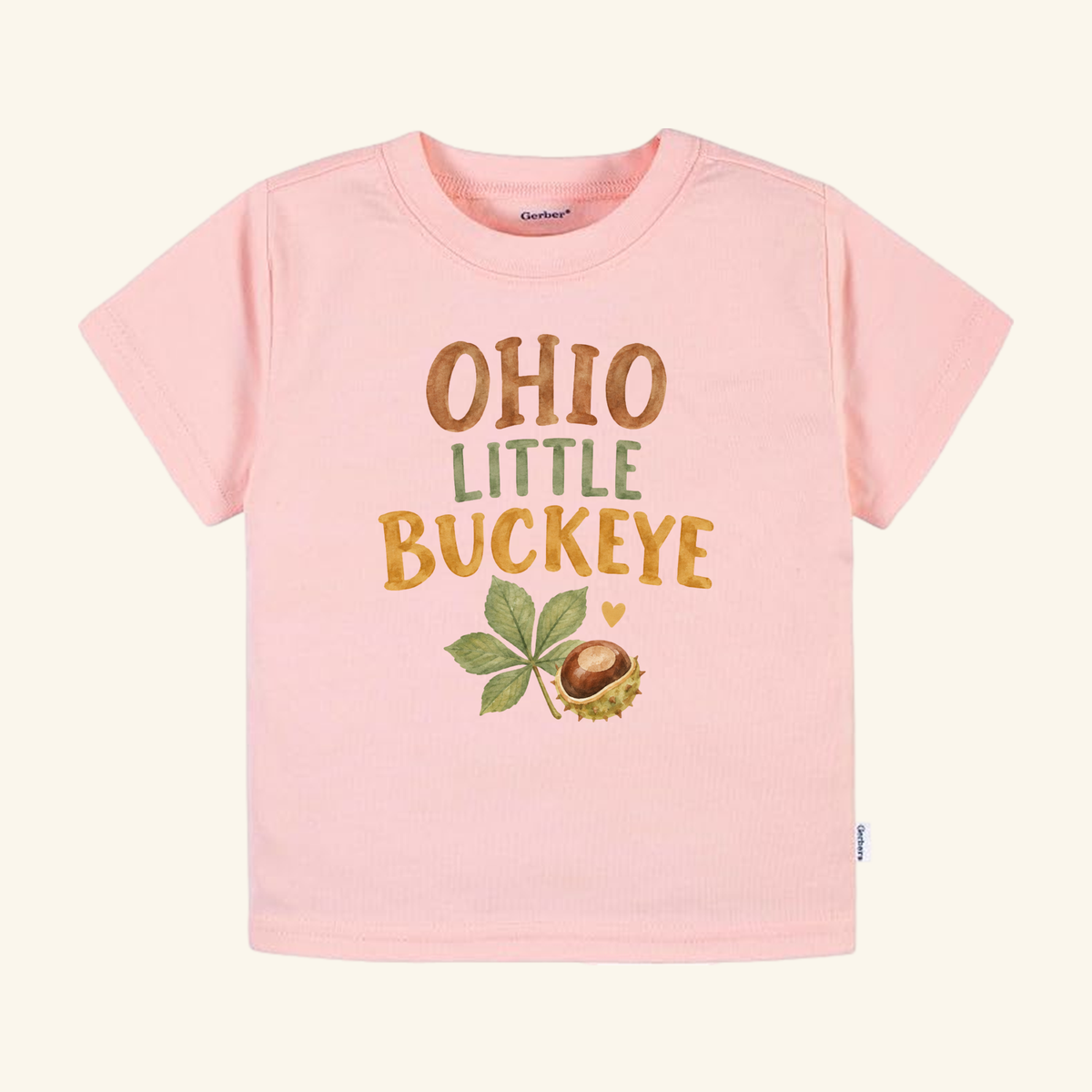 Ohio Toddler Shirt – Little Buckeye Watercolor Nut & Leaf Tee in light pink featuring the text OHIO LITTLE BUCKEYE in brown and green, with a watercolor illustration of a buckeye leaf and nut below.