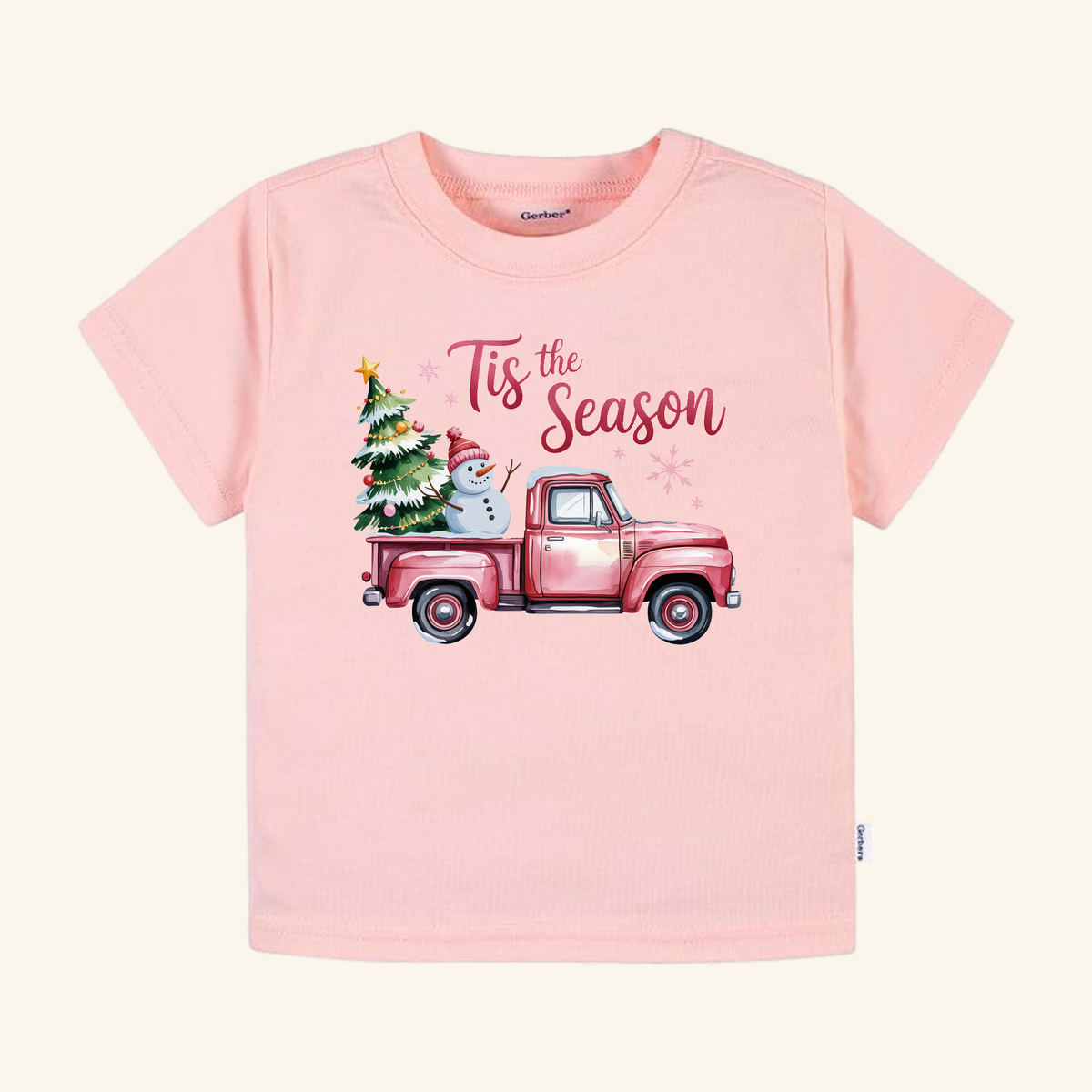 Pink Christmas Truck Toddler Shirt – ’Tis the Season Snowman Tee in light pink, featuring a red pickup truck carrying a decorated tree and a snowman with Tis the Season printed above.
