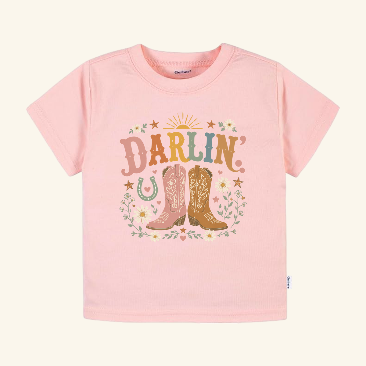 Toodleroos Toddler Cowgirl Shirt – Darlin’ Western Cowboy Boots Short-Sleeve Tee in light pink, featuring a graphic of two cowboy boots, a horseshoe, flowers, and the word DARLIN.