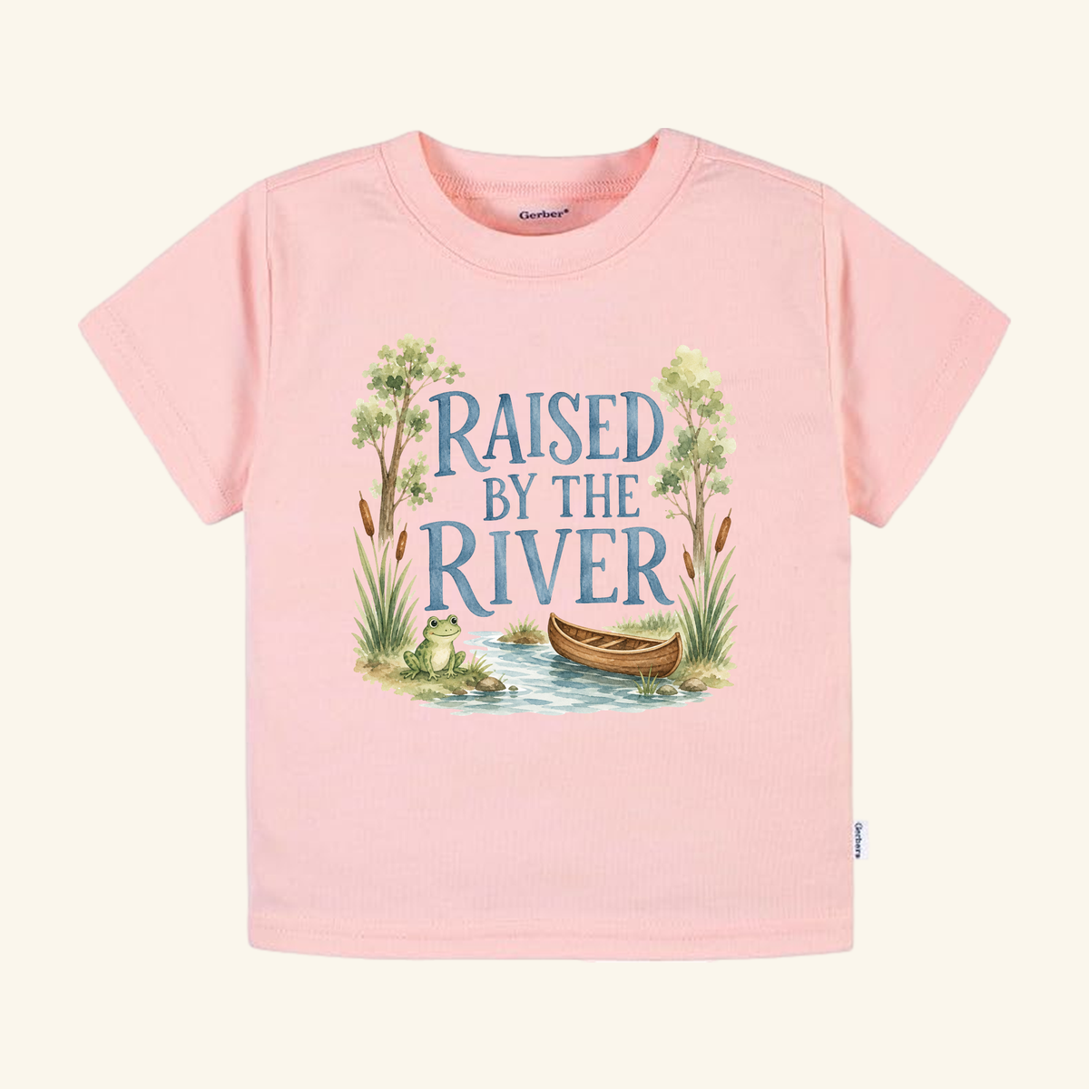 Raised by the River Toddler Shirt – Canoe & Frog Outdoor Tee in pink, featuring an illustration of a river scene with a canoe, a frog, and the text RAISED BY THE RIVER.