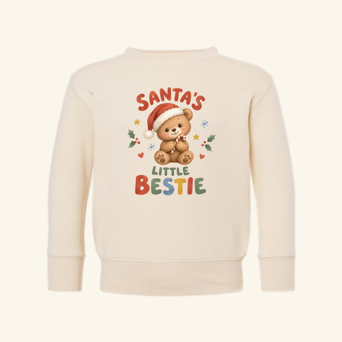Cream-colored Santa’s Little Bestie Toddler Sweatshirt – Teddy Bear Christmas Pullover featuring a teddy bear in a Santa hat holding a candy cane, surrounded by stars, snowflakes, and holly.