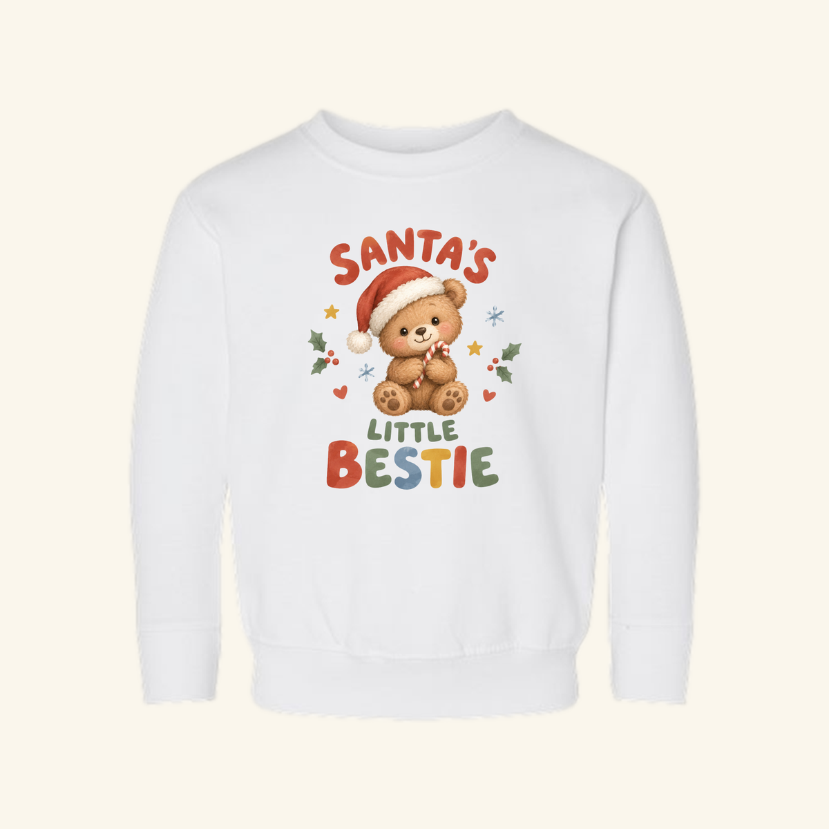 Toodleroos Santa’s Little Bestie Toddler Sweatshirt is a white Christmas pullover featuring a teddy bear in a Santa hat holding a candy cane, with SANTAS LITTLE BESTIE text surrounded by holly, hearts, and stars.
