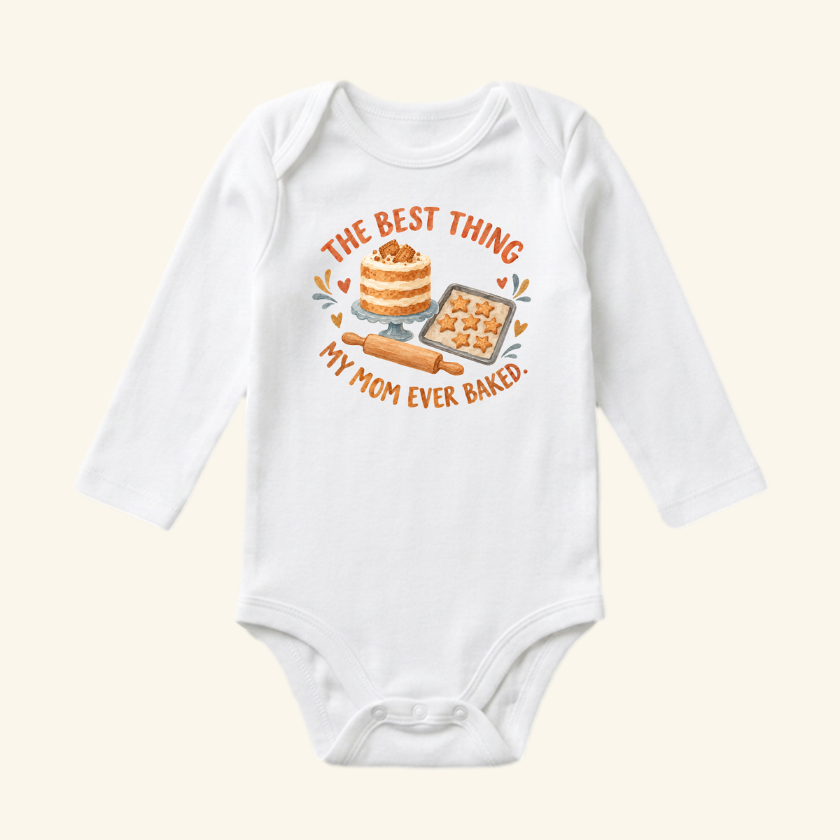 White long-sleeved Best Thing My Mom Baked Baby Onesie featuring a graphic of a layer cake, star-shaped cookies, and a rolling pin with the text, The best thing my mom ever baked.