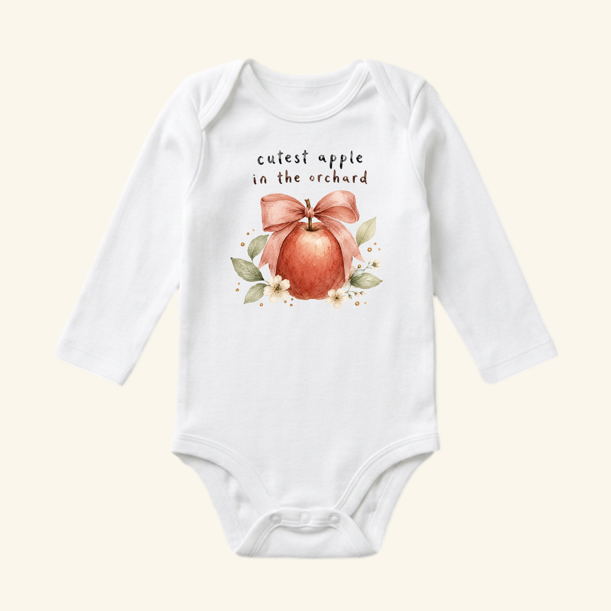 Toodleroos Cutest Apple in the Orchard Baby Onesie – Fall Apple Bow Bodysuit: a white long-sleeve onesie featuring an illustration of a red apple with a pink bow, surrounded by leaves and the text, cutest apple in the orchard.