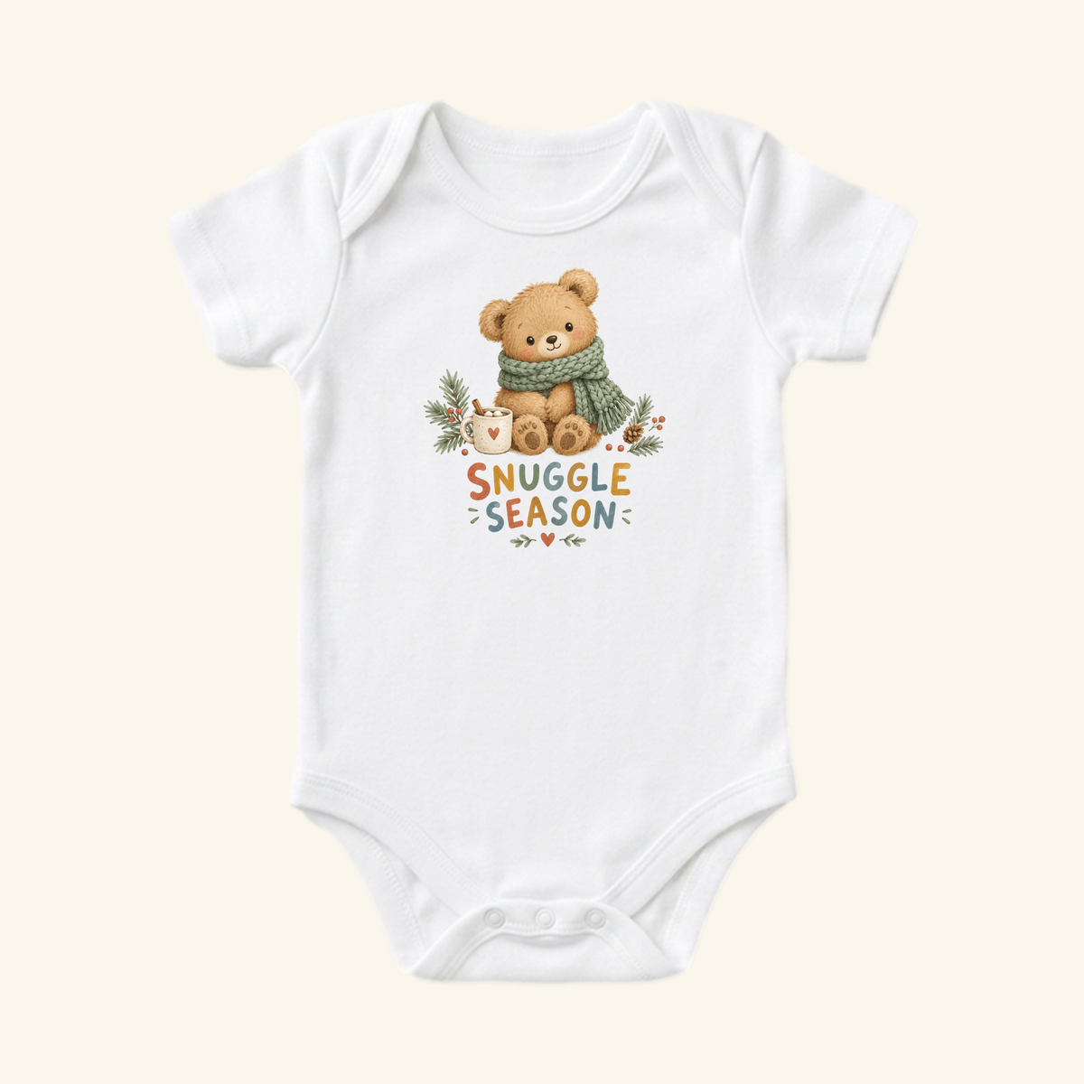 Toodleroos Snuggle Season Baby Onesie – Cozy Winter Teddy Bear Bodysuit featuring a teddy bear wearing a green scarf sitting next to a mug, with the text Snuggle Season below.