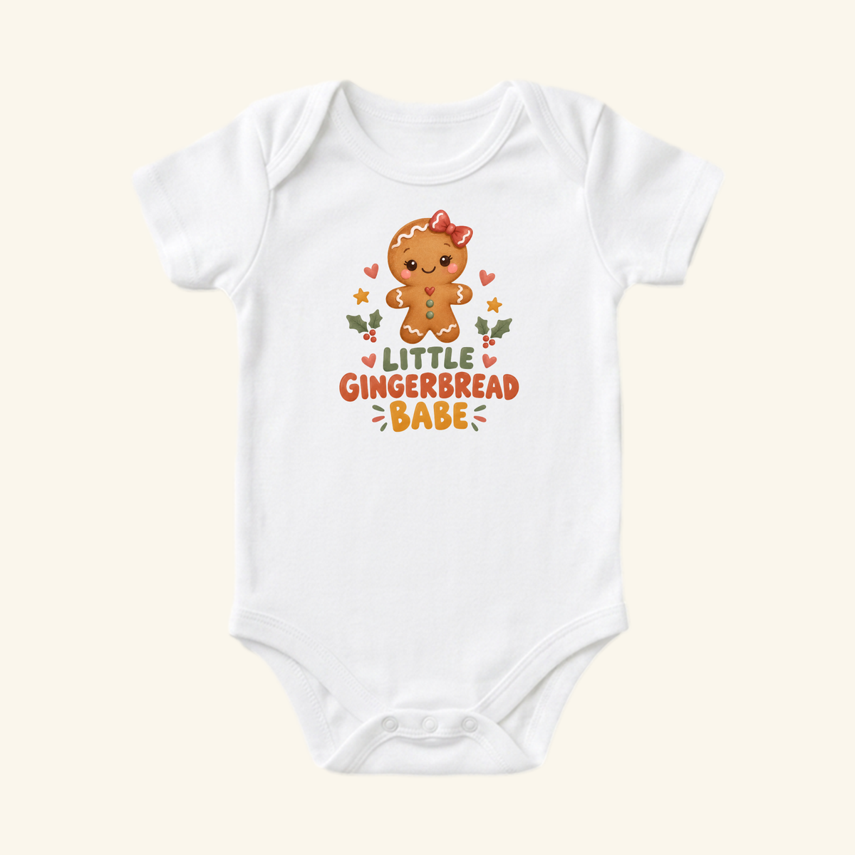 Toodleroos Little Gingerbread Babe Baby Onesie, a white Christmas bodysuit featuring a gingerbread cookie with a red bow, the text Little Gingerbread Babe, and small hearts, stars, and holly leaves.
